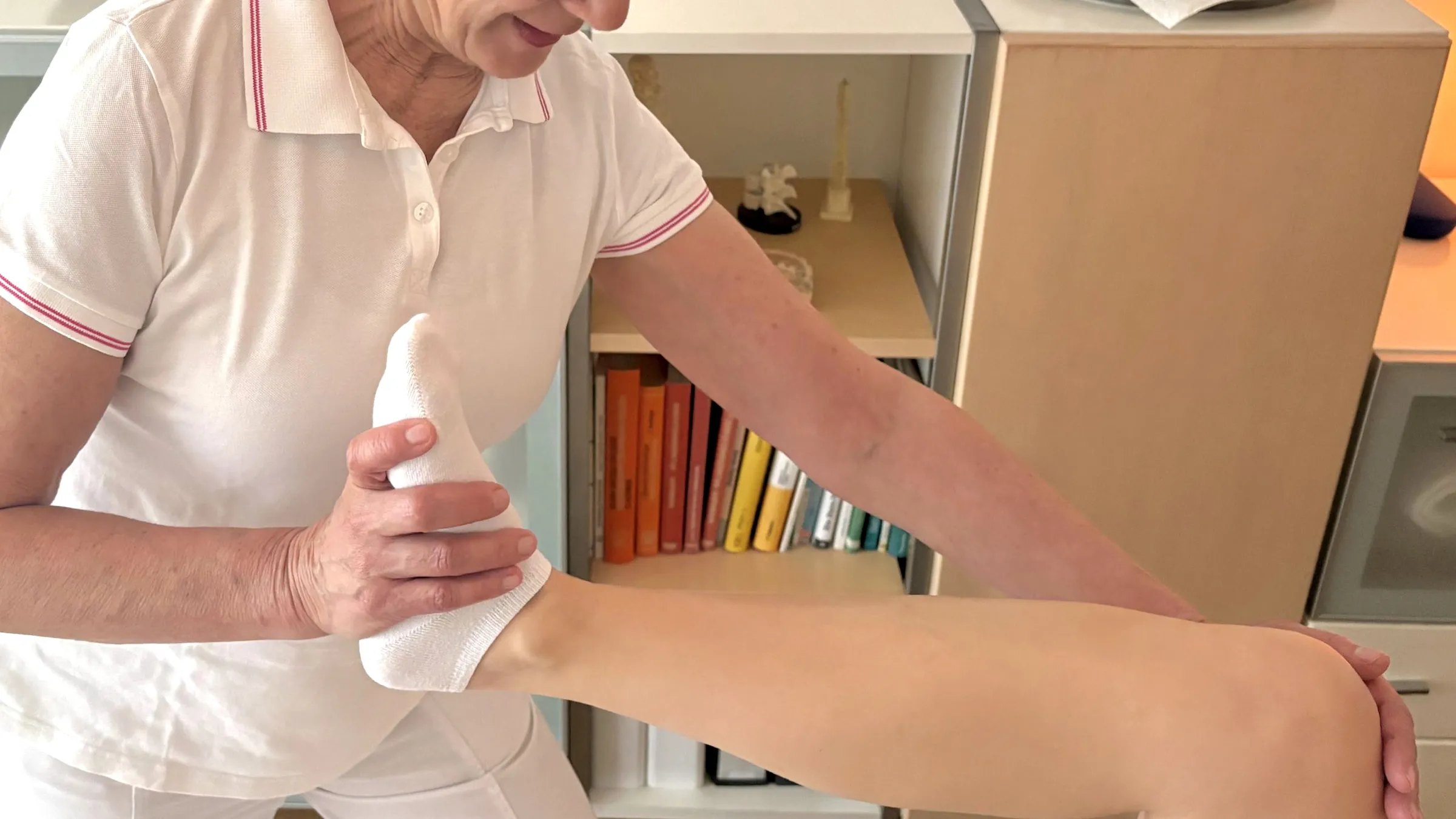 Astrid Schweizer behandelt mit beiden Händen das Bein einer Patientin