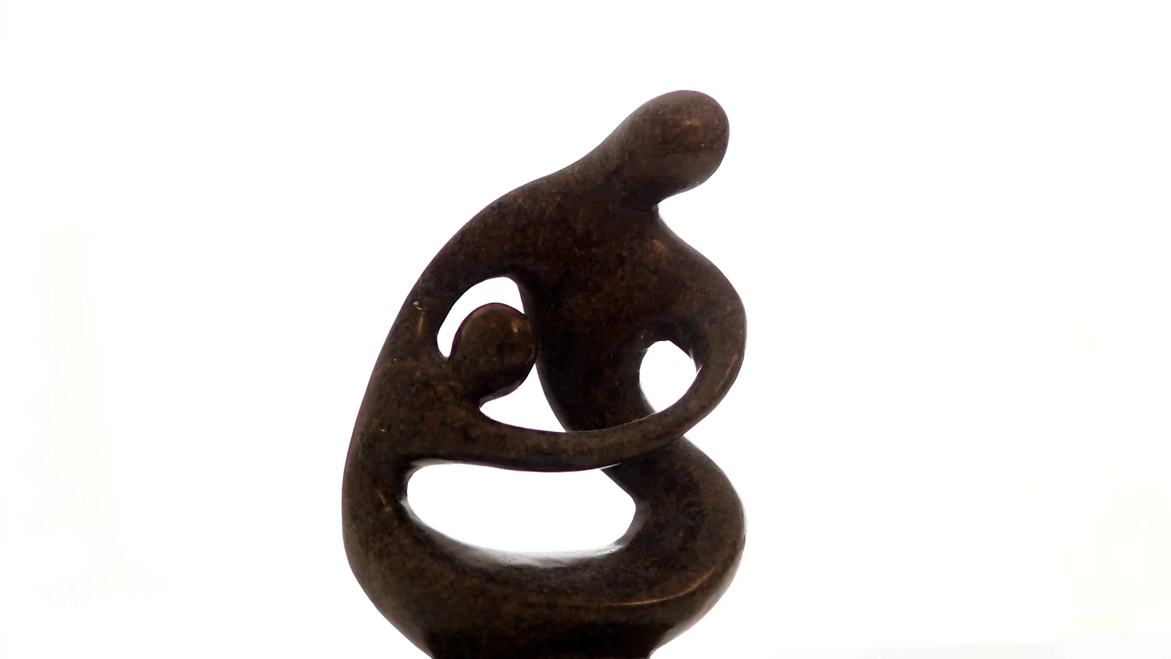 Eine dunkle Steinskulptur: eine Figur, die eine zweite umschließt